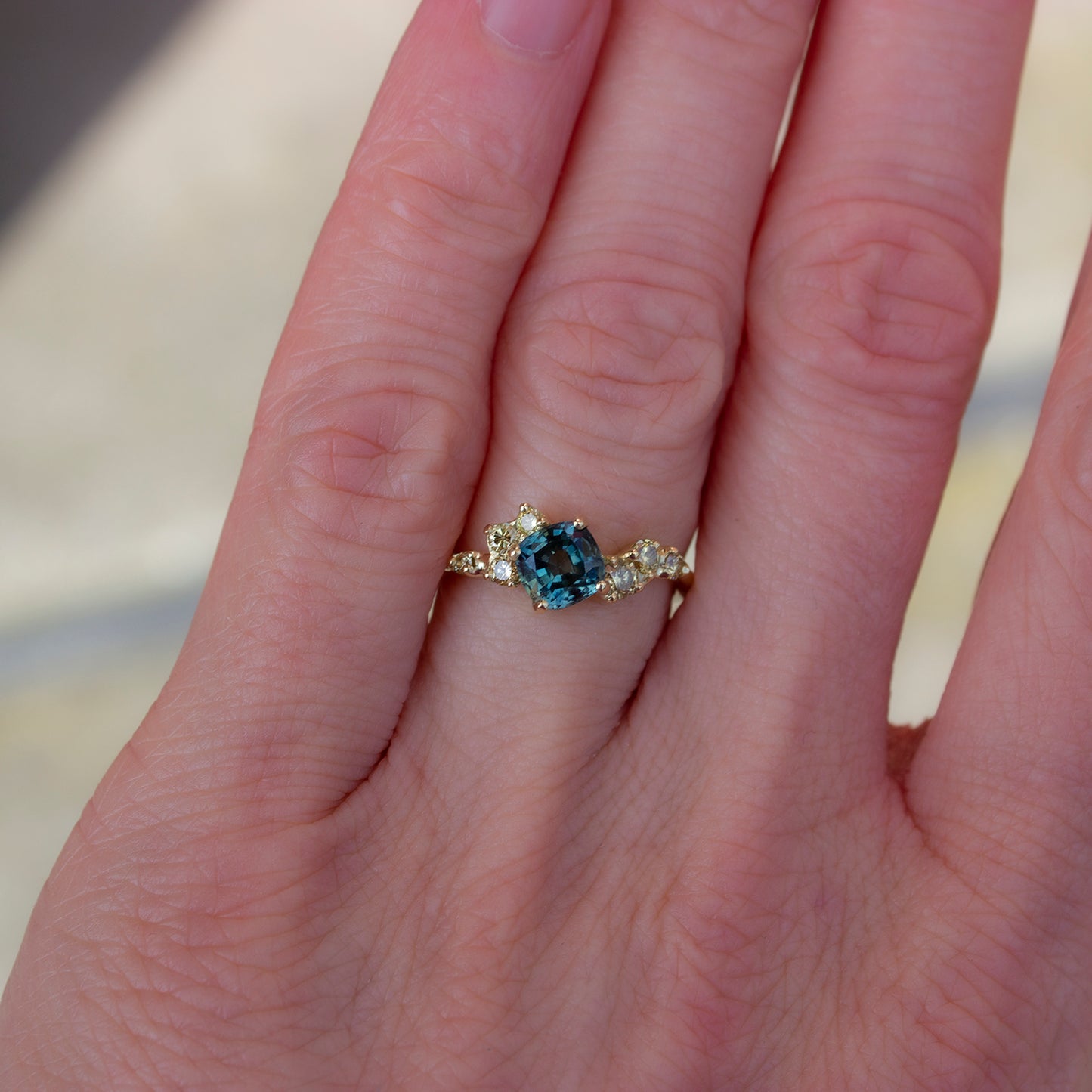 Beautiful, organically shaped ring featuring teal cushion cut sapphire surrounded with asymmetrically scattered yellow diamonds.