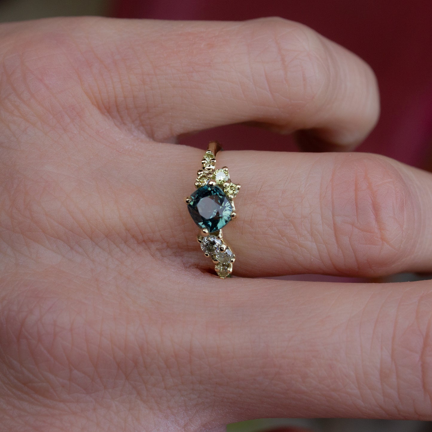 Beautiful and delicate alternative engagement ring featuring cushion cut teal green Montana sapphire flanked by yellow diamonds gently scattered along the band. Resembling first flower buds this ring was inspired by.