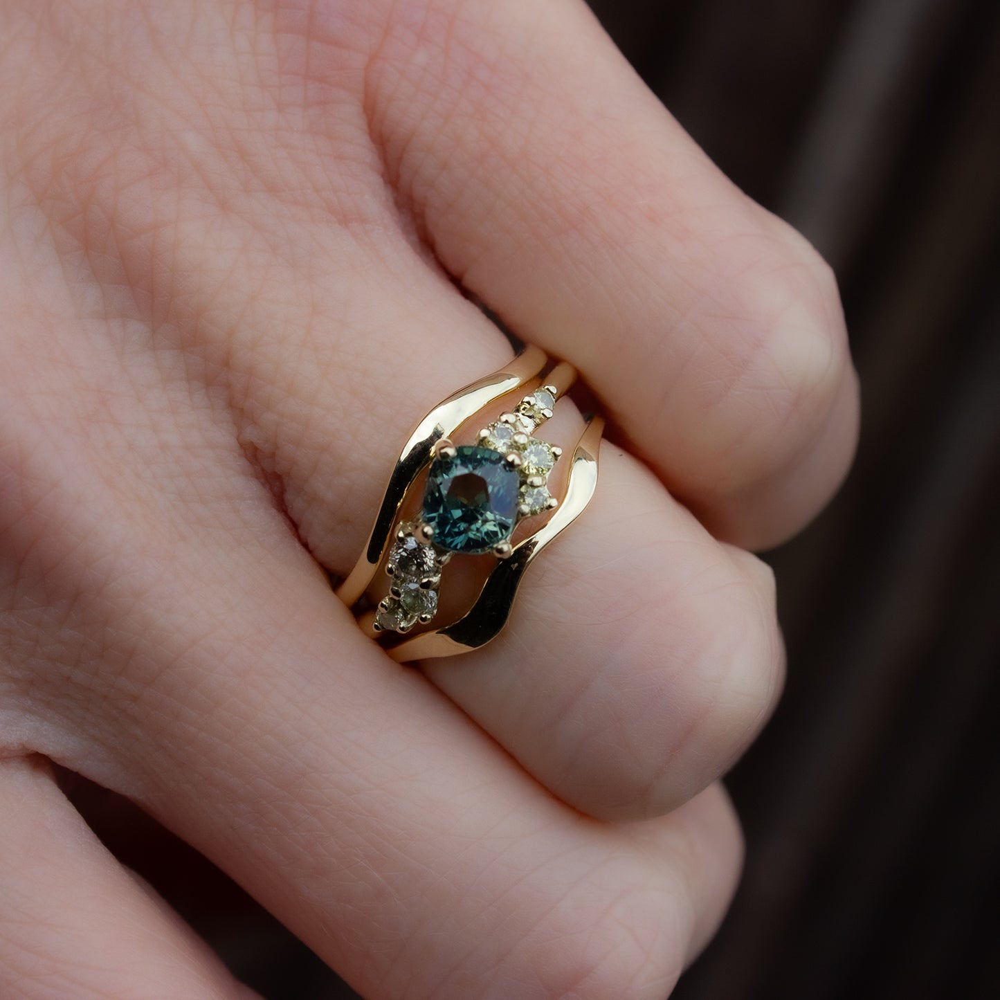 Beautiful and delicate alternative engagement ring featuring cushion cut teal green Montana sapphire flanked by yellow diamonds gently scattered along the band. Resembling first flower buds this ring was inspired by. Showcased with a perfectly curved wedding band, designed to gently hug the ring.