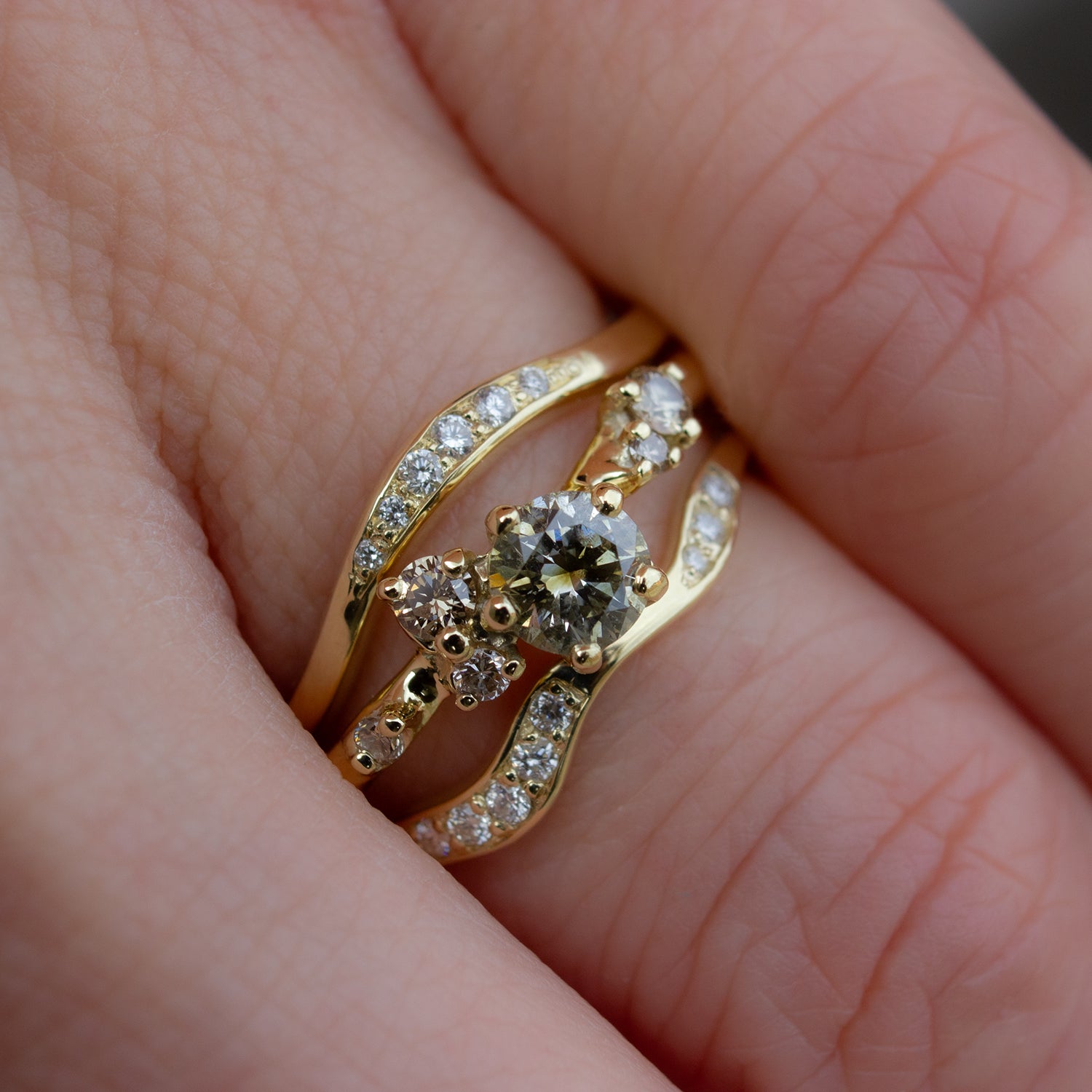 Beautiful and delicate alternative engagement ring featuring champagne diamonds gently scattered along the band. Resembling first flower buds this ring was inspired by. Ring is hugged with two delicately curved wedding bands, both glimmering with white diamonds.