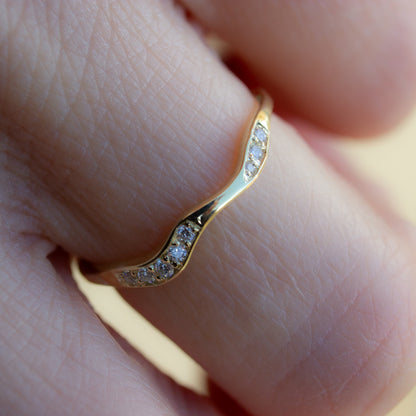Curved shaped gold wedding band with pavé set white diamonds