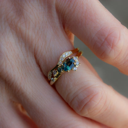 Teal sapphire and diamonds alternative engagement ring shown with a perfectly matching, curved wedding band. Band is glimmering with pavé set white diamonds