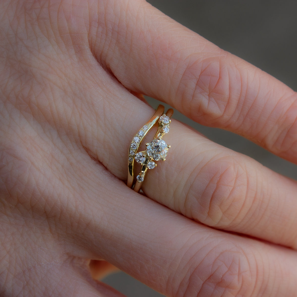 Alternative engagement ring featuring old cut white diamond surrounded by brilliant cut diamonds and inspired by florals. Ring is coupled with perfectly matching, curved gold wedding band, glimmering with diamonds.