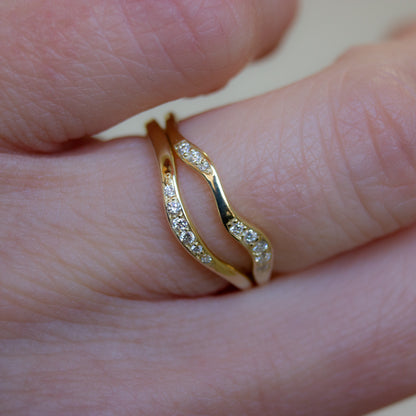 Two gently shaped gold wedding bands with pavé set white diamonds. Arc and flow shaped bands, designed to match our alternative engagement rings.