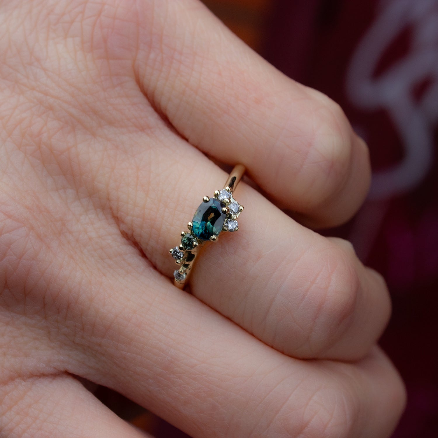 Alternative engagement ring featuring central green parti sapphire, smaller green sapphire and salt and pepper diamonds scattered organically along the band.