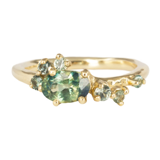 Beautiful alternative engagement ring featuring teal sapphbires scattered organically along the band.