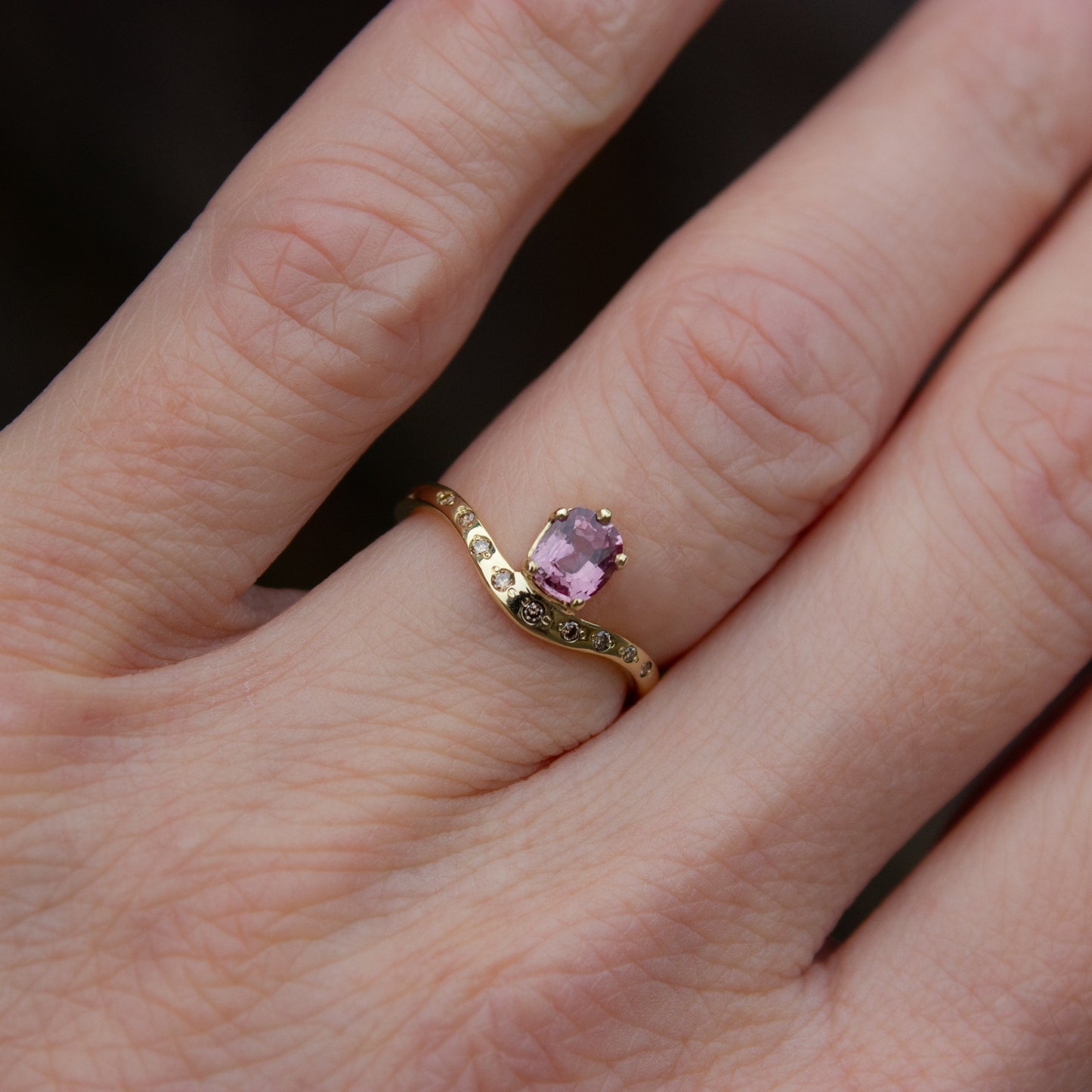 Delicate curved ring in gold featuring cushion cut pink padparadscha sapphire and champagne diamonds. Irena Chmura Jewellery