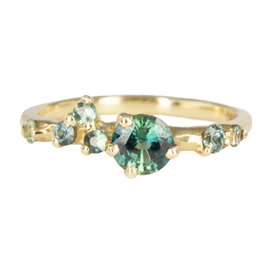 Asymmetrical, delicate ring featuring beautiful teal sapphires scattered along a gold band.